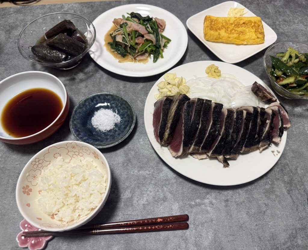 鰹のたたきと卵焼き、野菜のおかず、ご飯を並べた食卓