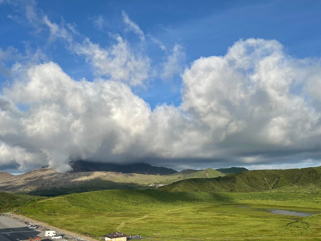 阿蘇で見た、青空と大きな白い雲、山々と緑の草原が広がる景色