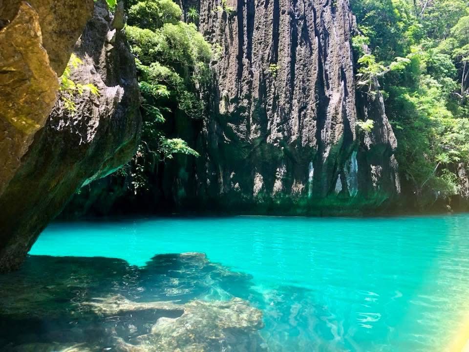 高い岩壁に囲まれたフィリピンの鮮やかな青緑色の海